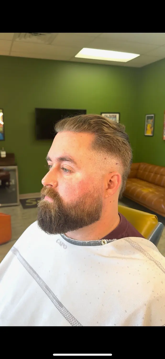 Slicked-back fade with full beard at One For All Barbershop